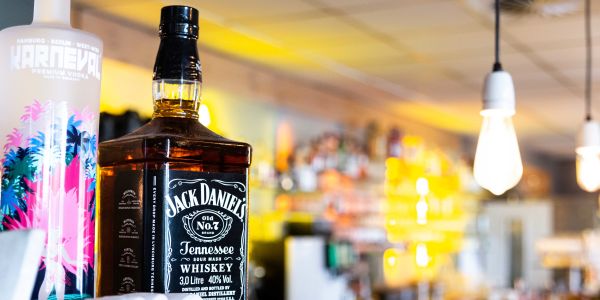 Vodka und Jack Daniels Whiskey Flasche vor tiefenunscharfer Bombastic Bar Theke
