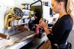 Barista beim Aufschäumen von Milch an einer professionellen Siebträgermaschine.
