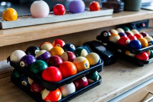 Detailaufnahme von bunten Billardkugeln in schwarzen Ablagen und im Regal.
