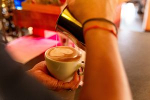 Close-up: Barista gießt ein Latte Art Herz in eine weiße Kaffeetasse.
