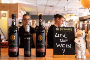 Zwei Flaschen Chianti Classico und eine kleine Flasche Merlot stehen auf der Bar neben einer Tafel mit der Aufschrift „Lust auf Wein?“.