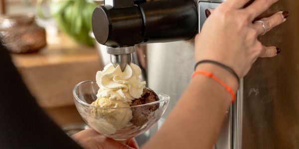 Zubereitung eines Eisbechers mit frischer Sahne aus der Maschine.