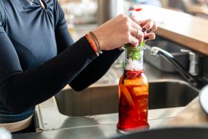 Barkeeperin garniert einen roten Cocktail in einer Karaffe mit Minze.
