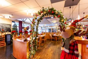 Beleuchteter Torbogen aus Tannengrün mit großen Stoff-Rentieren.
