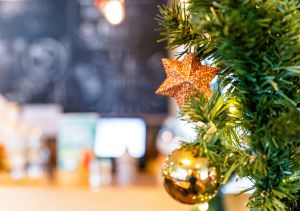 Detailaufnahme eines Weihnachtsbaums mit goldenem Stern und Kugel.
