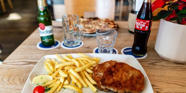 Schnitzel mit Pommes und Getränken auf einem Restauranttisch.