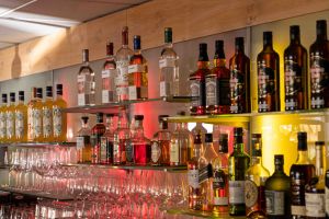 Gut gefüllte Regalböden hinter der Bar mit einer großen Auswahl an Spirituosen und ordentlich aufgereihten Weingläsern.