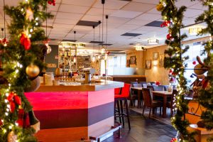 Beleuchtete Bar mit rotem Licht, eingerahmt von Weihnachtsgirlanden.
