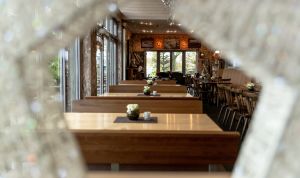 Blick durch einen dekorativen Stern hindurch in den leeren Gastraum mit Holzbänken.
