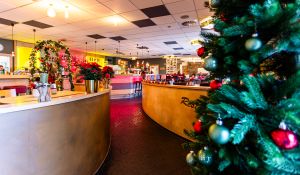 Restaurant-Innenraum mit geschwungener Theke und Weihnachtsbaum.
