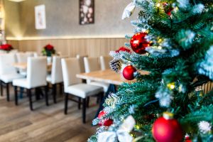 Weihnachtsbaum mit roten Kugeln vor hellem Essbereich.
